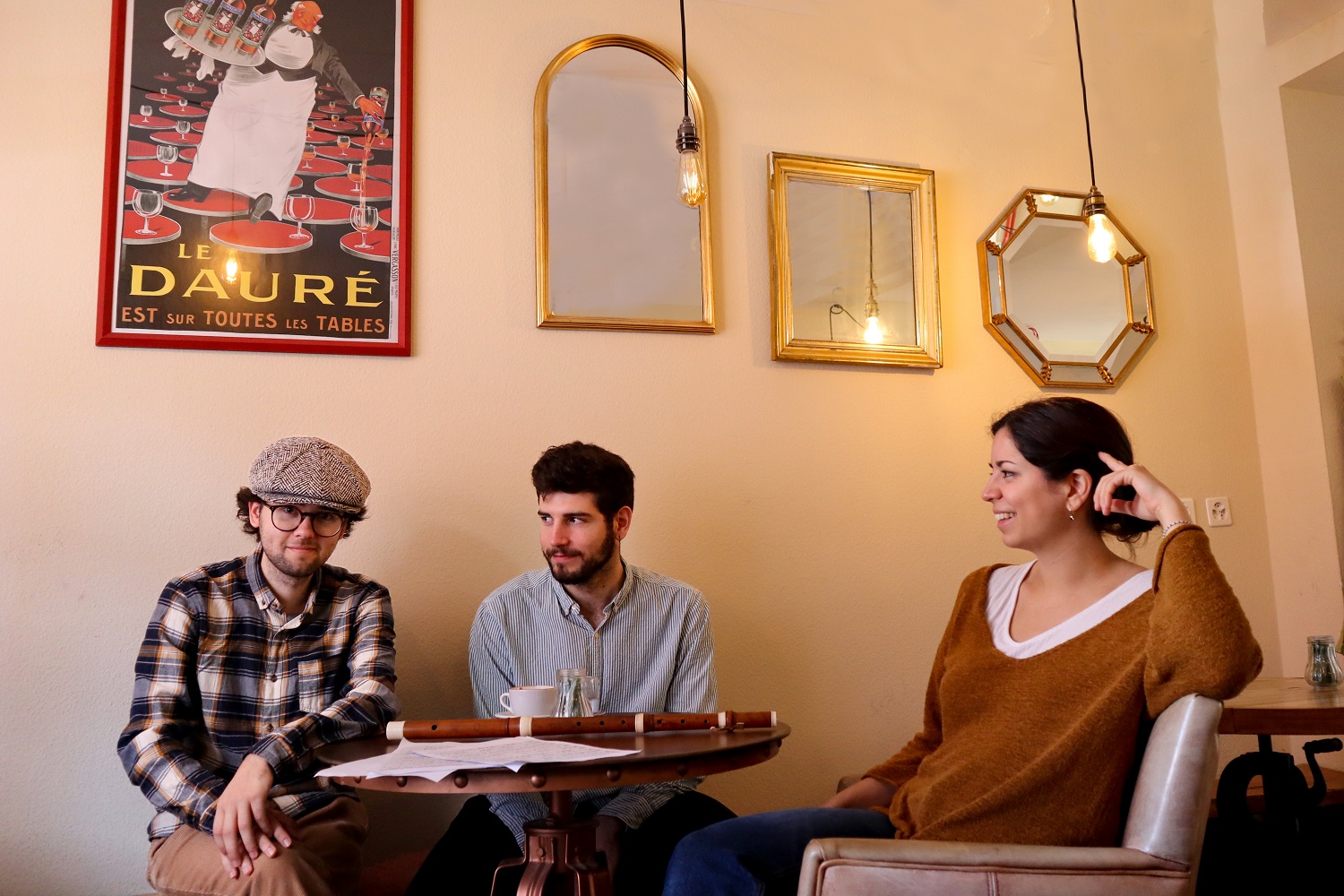 Drei junge Menschen sitze um einen Tisch in einem Café